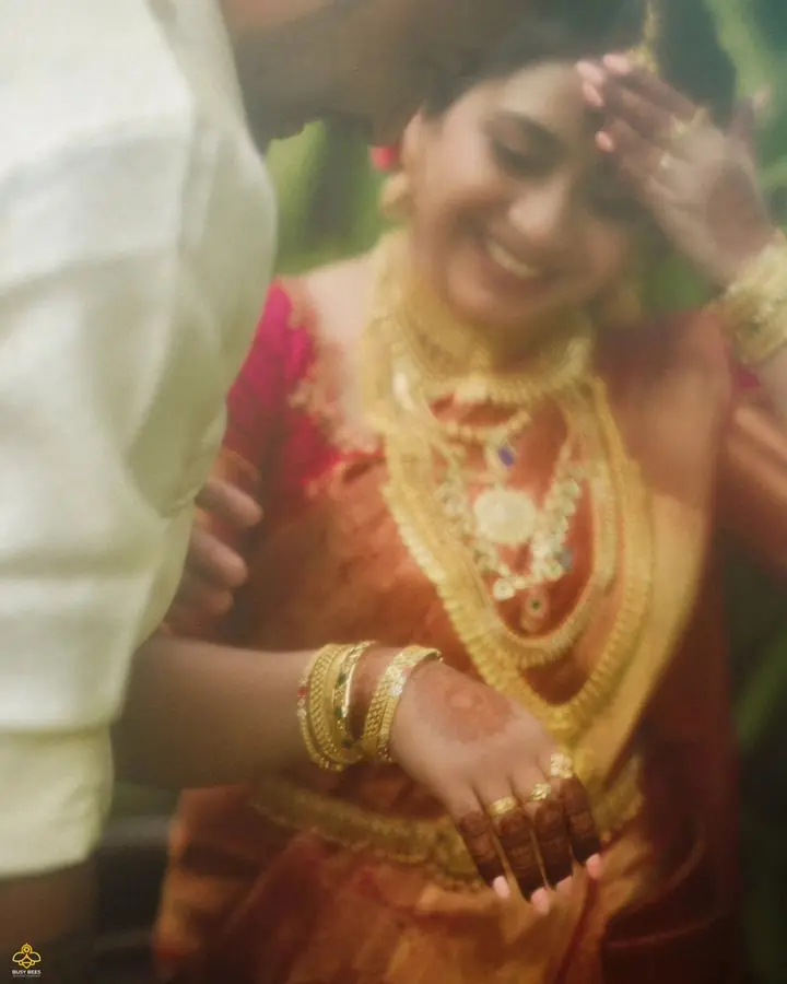 Bride laughing in red silk and layered temple gold, caught mid-movement