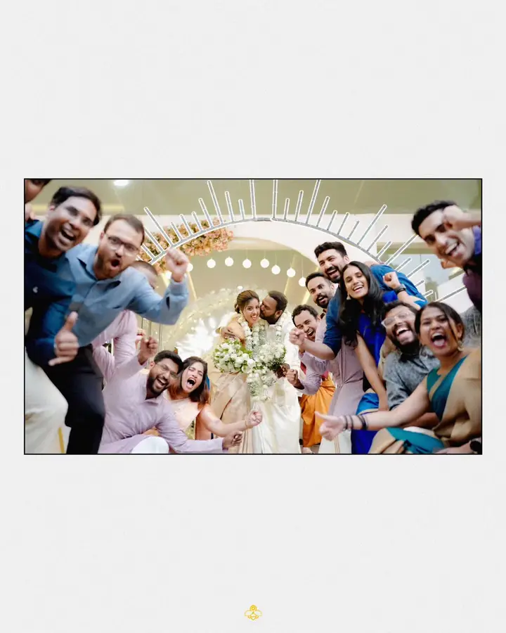 Friends cheering around the bride and groom under a lit floral arch