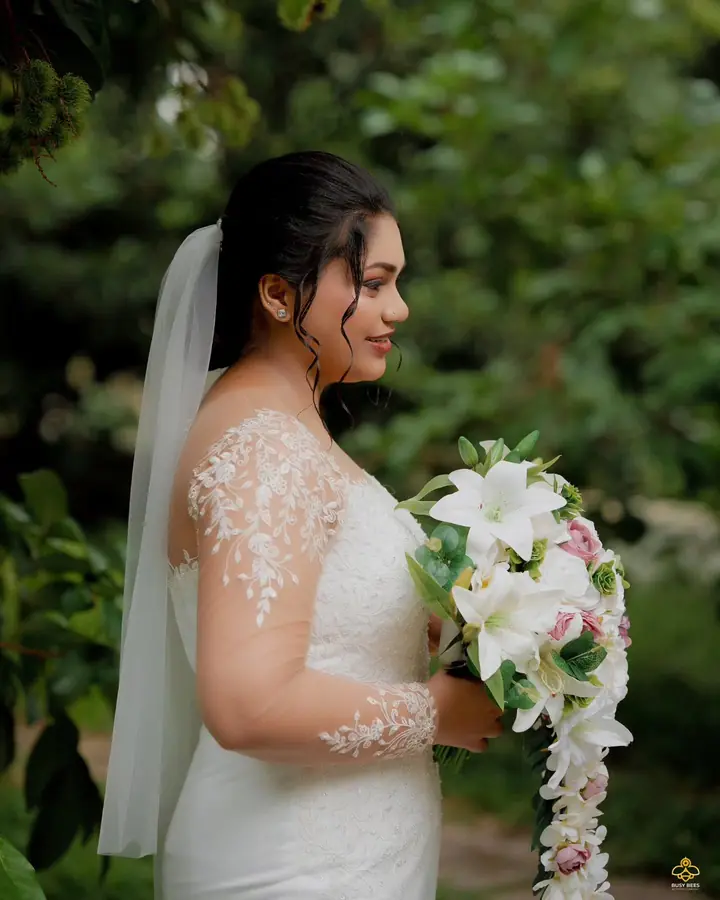 Bride in a lace gown and veil holding a bouquet of white lilies