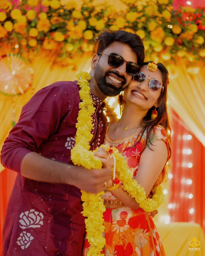 Couple in marigold garlands and sunglasses at the haldi celebration