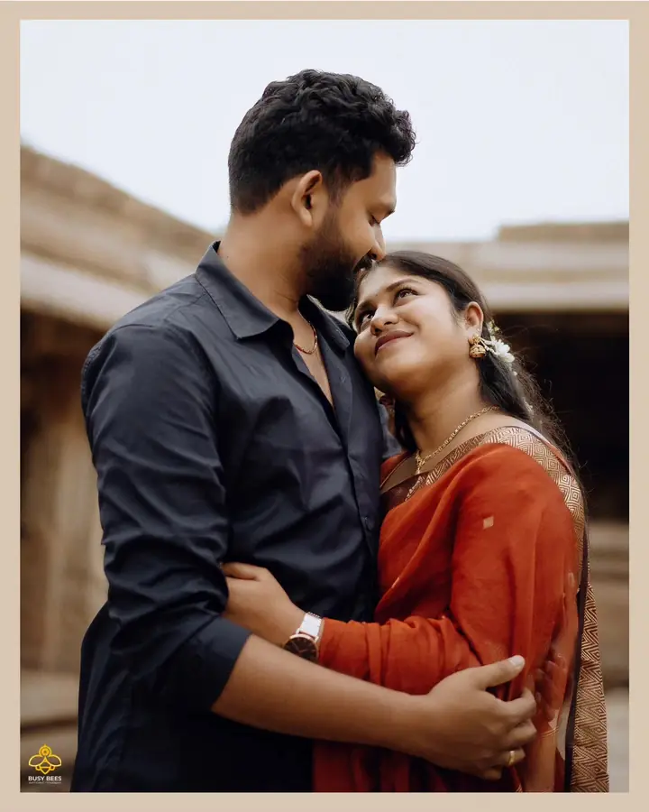 Couple hold each other close, the bride in a rust silk saree