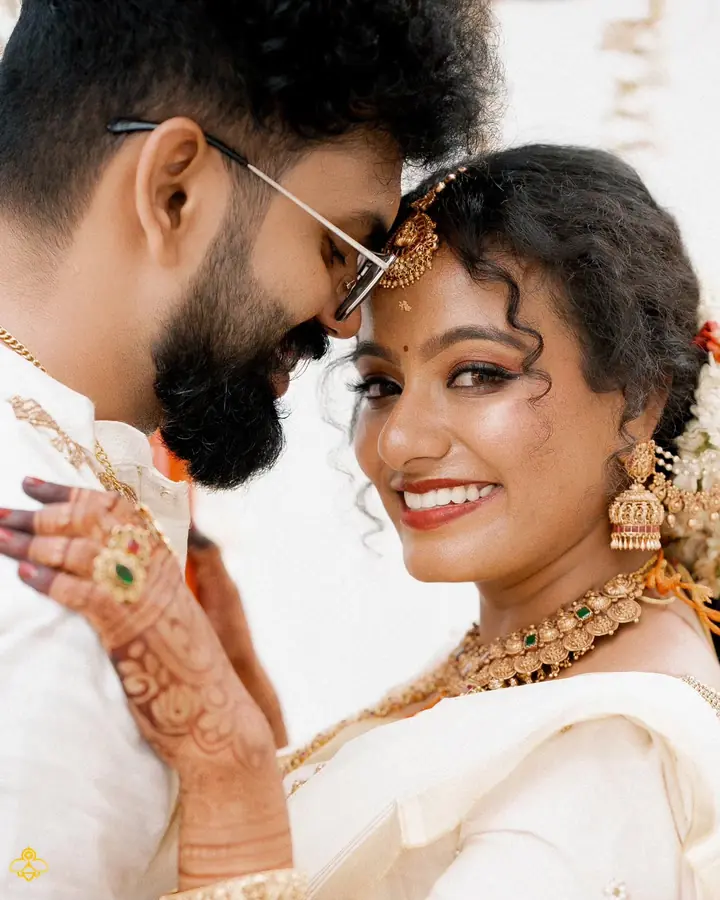 Bride and groom rest their foreheads together, gold jewellery catching the light